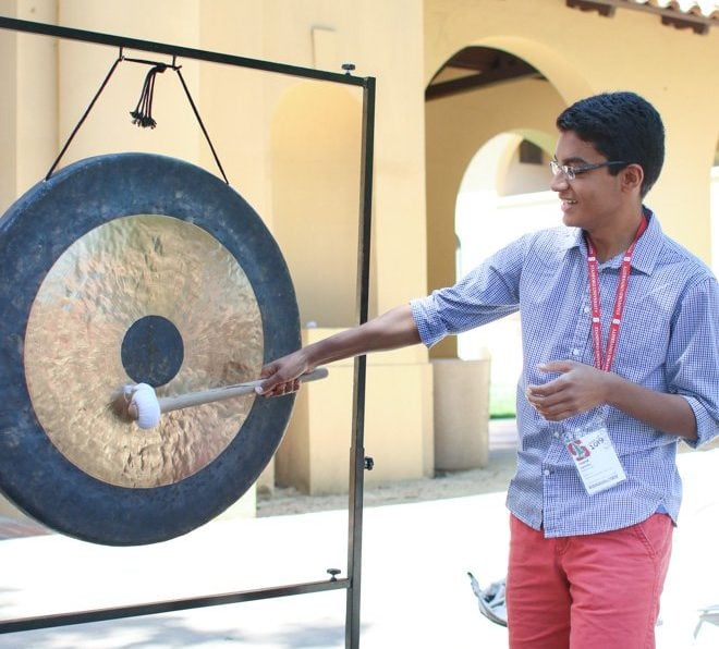 An incoming student hits a gong in front of Old Union, signaling that they have decided to attend Stanford.