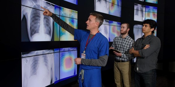 radiologist Matt Lungren, M.D., left, meets with graduate students, Jeremy Irvin and Pranav Rajpurkar to discuss the results of tests using the algorithm the students developed.
