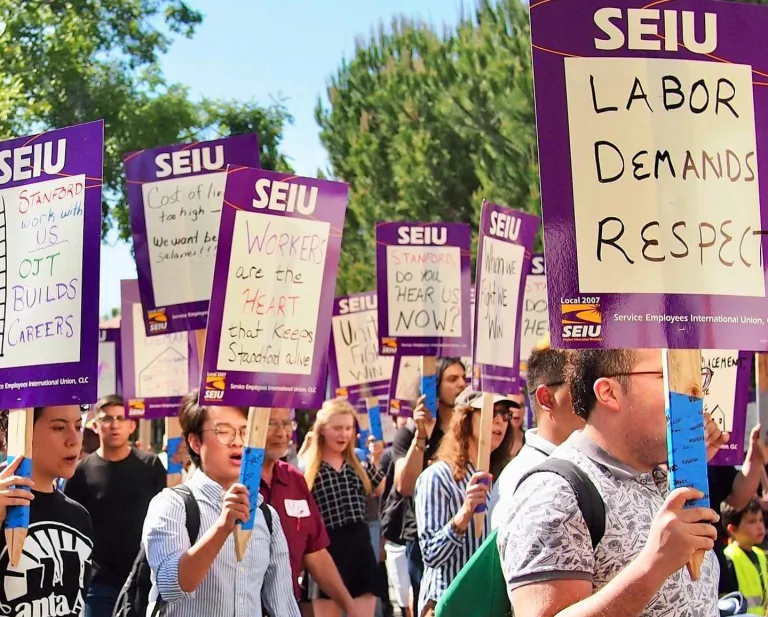 A group of SEIU protestors gather holding signs.