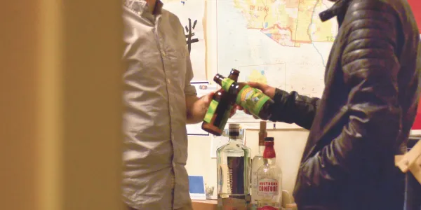 Students clink alcohol bottles together.