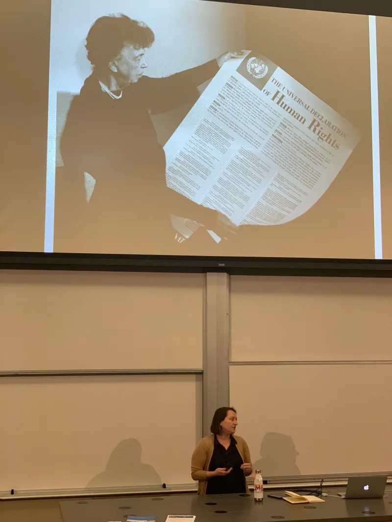 Executive Director of HRDAG Megan Price stands beneath a photo of Eleanor Roosevelt holding "The Universal Declaration of Human Rights." (Photo: EMMA TALLEY/The Stanford Daily)