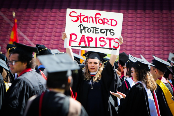Many students at the open forum set their Zoom background image to be a photo of a student holding up a "Stanford protects RAPISTS" sign at the Class of 2016's commencement. (Photo courtesy of Ella Booker)