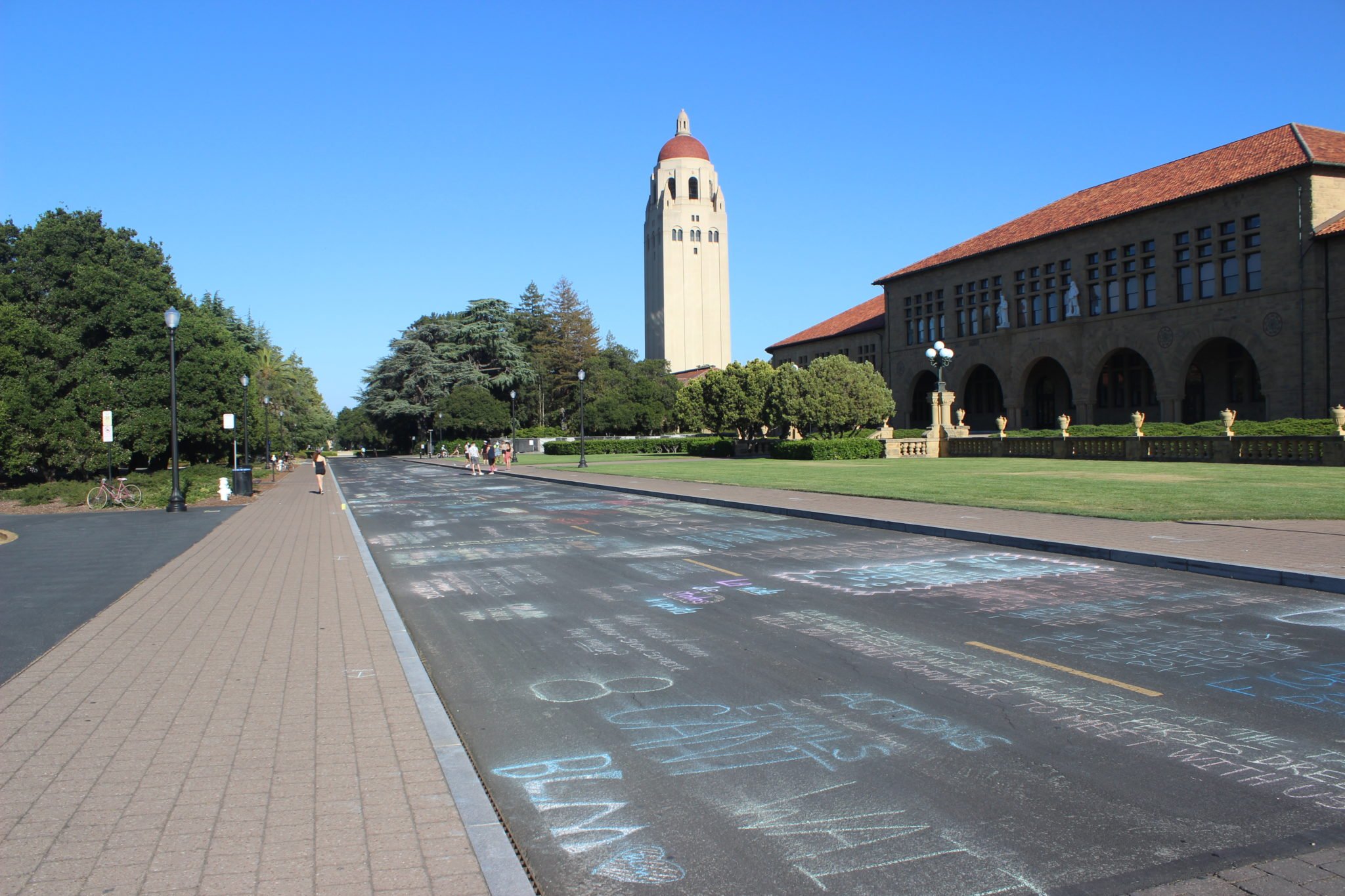 View of chalk along Jane Stanford Way, with the front of Main Quad on the right and Hoover Tower in the background