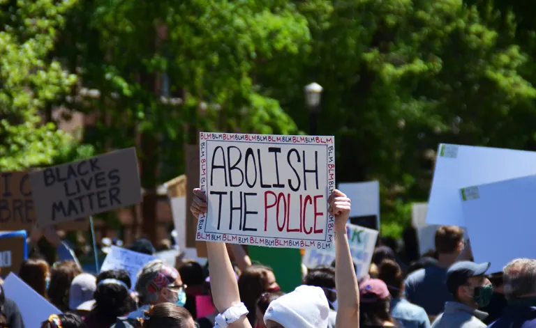 Protest crowd with a sign reading "Abolish the police" held in the air