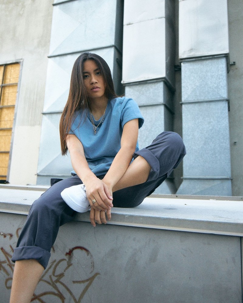 Emily Vu sits on a ledge in an urban environment.