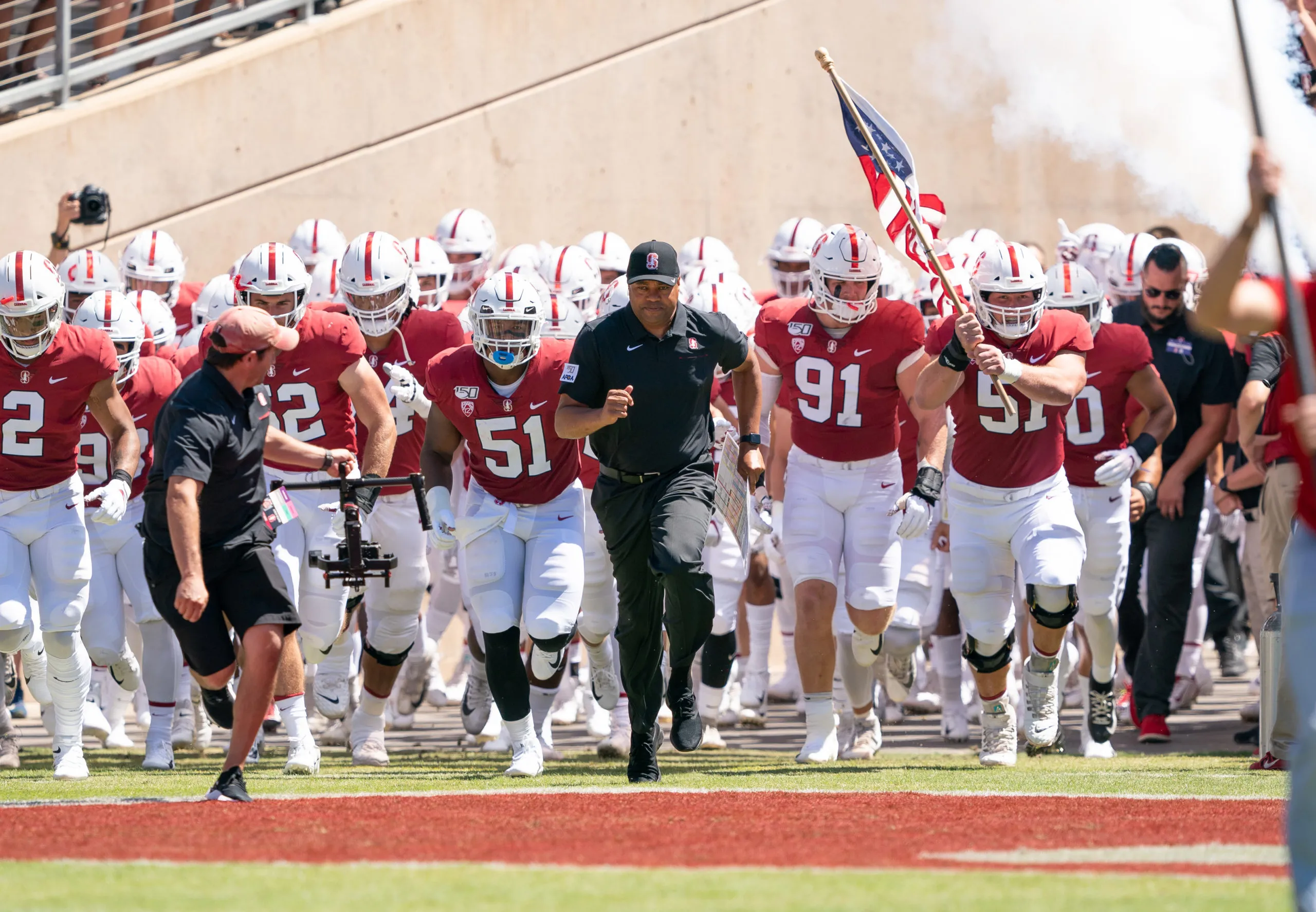 The Stanford football team runs out onto the field at the start of a game.
