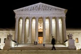 A blurred figure walks in front of the Supreme Court at night. (Photo: Wikimedia Commons)