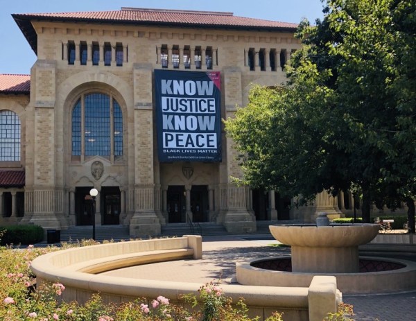 A black-and-white banner with the phrase, "know justice, know peace," hangs on the Bing (West) Side of Green Library