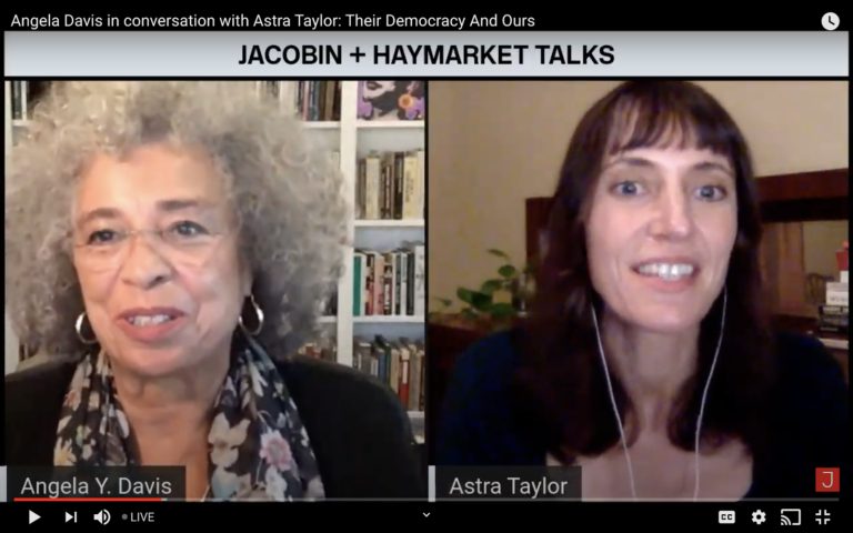 A screenshot of a YouTube livestream that show Angela Davis and Astra Taylor, on a video conference, in front of their respective bookcases