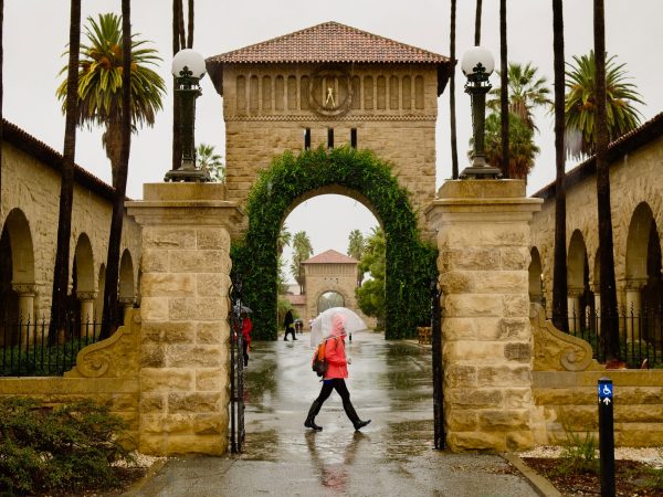 person walks by stanford ivy arch during a wet day