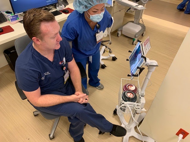 Emergency medicine doctor Ryan Ribeira uses an iPad to communicate with the patient instead of having to use PPE and go into the room. (Photo Courtesy of Stanford Medicine)