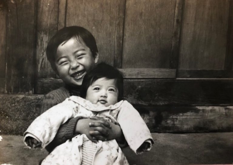 Pictured: a black-and-white photograph of a young boy and his baby sister