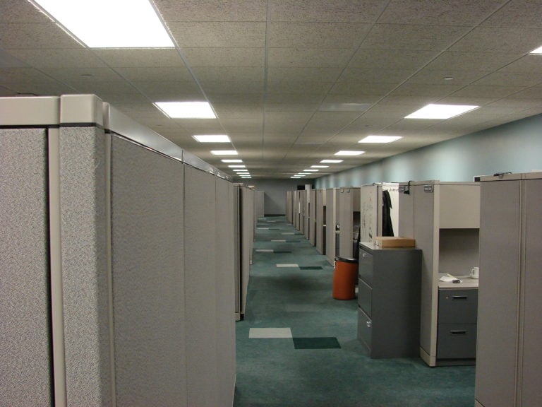 a starkly lit office row of empty cubicles