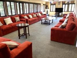 A room with long red couches and coffee tables.