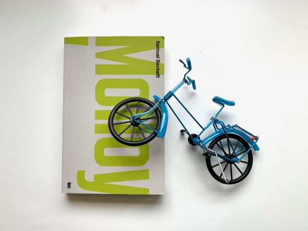 a plain cover of "Molloy" with the title in green text, and a blue plastic bicycle