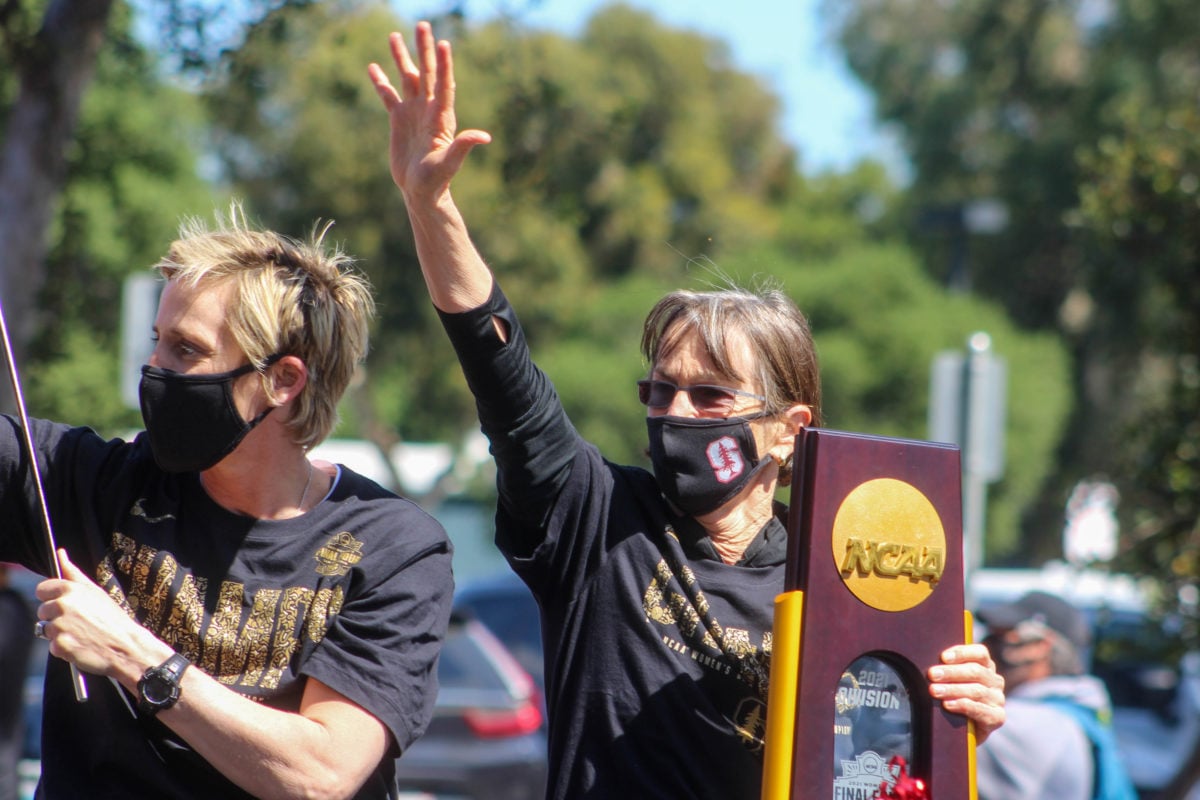 A close shot of Tara VanDerveer as she waves to a crowed at the Oval holding the NCAA trophy.