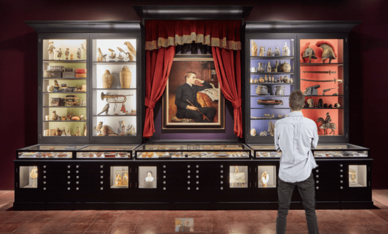 A man facing a wall of artwork.