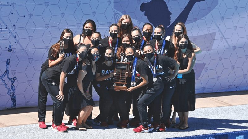 Members of the synchronized swimming team gather for a picture with the championship trophy on the deck of Avery Aquatic Center
