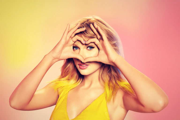 Taylor Swift makes a heart with her hand over her eyes