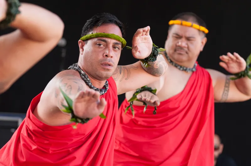 Hawaiian dancers with green and yellow headresses and red clothing
