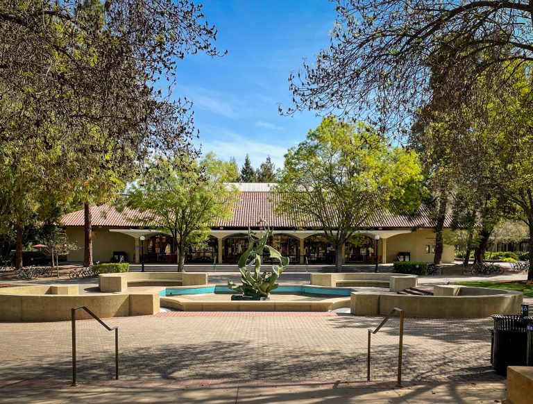 The Claw fountain sits in front of Stanford Bookstore, surrounded by trees in an empty White Plaza