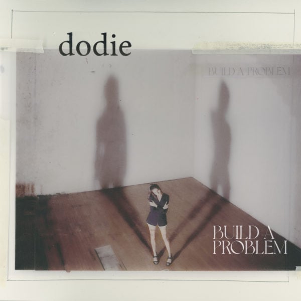 Dodie stands in a room with shadows on the wall