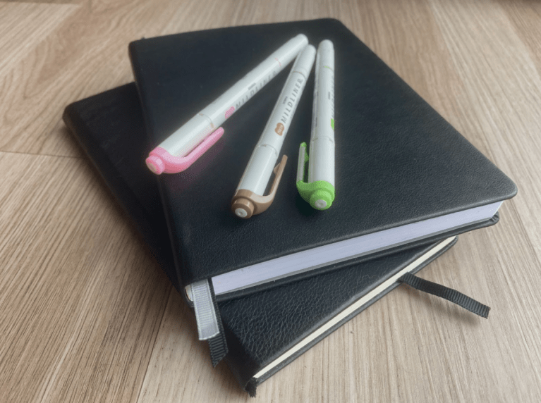 A stack of journals with pens.