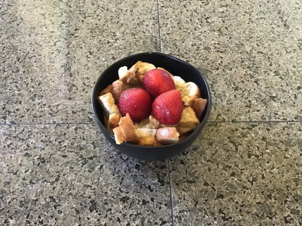 A bowl of french toast strips topped with strawberries