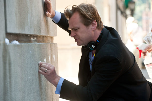 Christopher Nolan writes on a wall in chalk.
