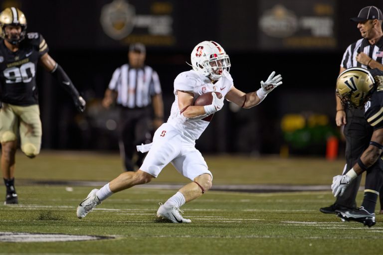 Running back Casey Filkins runs down the field carrying the football with Vanderbilt players in the background.