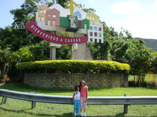 Melissa, age 4, and her older sister pose for a picture in front of the Caguas town sign located in the center of Puerto Rico.