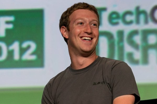 Mark Zuckerberg smiling in front of a presentation