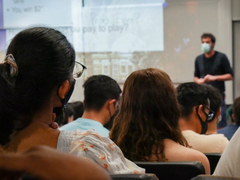 A professor teaches in a room of student wearing masks