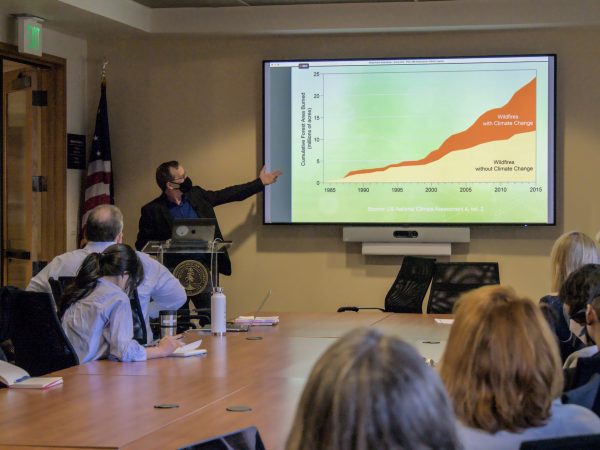 Paul N. Edwards presents conclusions of United Nations climate change report, pointing towards presentation slide that shows increase in wildfires due to climate change.