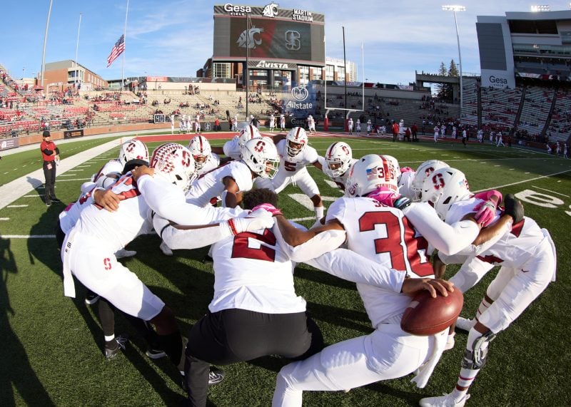 A group of football players huddle up together on the field.