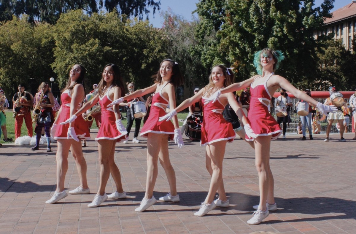 Five Stanford dollies pose outside Green library with their hands outstretched.