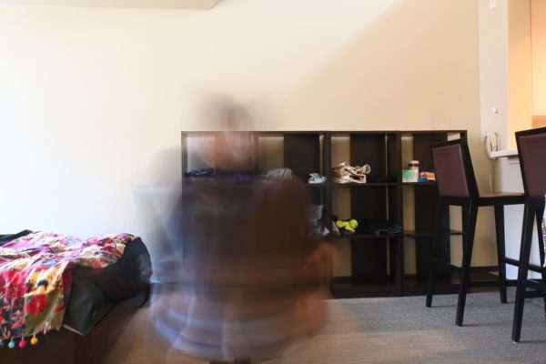 An overexposed photograph of a dorm room with a blurry figure in the foreground