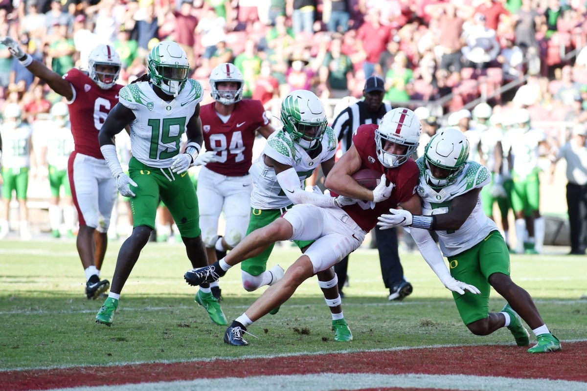 Sophomore wide receiver John Humphreys falls to the ground at the touchdown line with two Oregon defenders on either sides of him. Two Stanford players and one Oregon player move towards the group from behind.