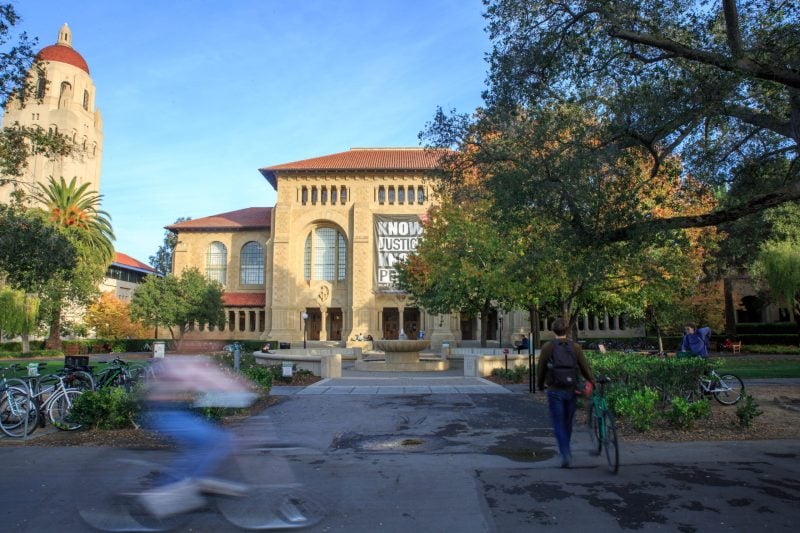 Bikers pass in front of Cecil H Green Library at Stanford University