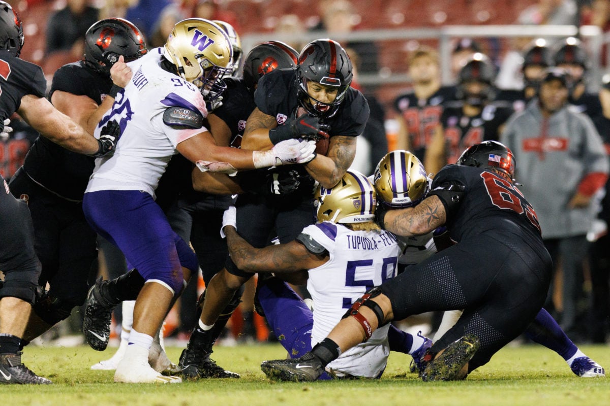Stanford and Washington players crash into each other, some falling and some on the ground. 