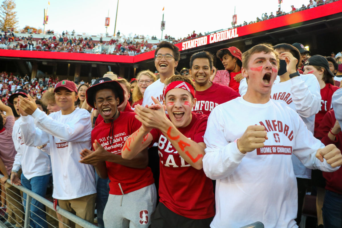 A crowd of Stanford students dressed in red and white cheeer. 