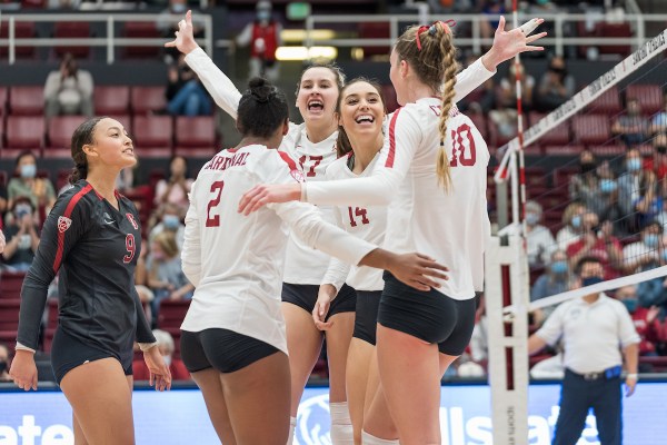 Stanford women's volleyball players celebrate near the net following a point.