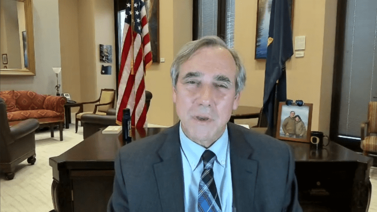 Senator Jeff Merkley speaking over zoom from in front of his desk.