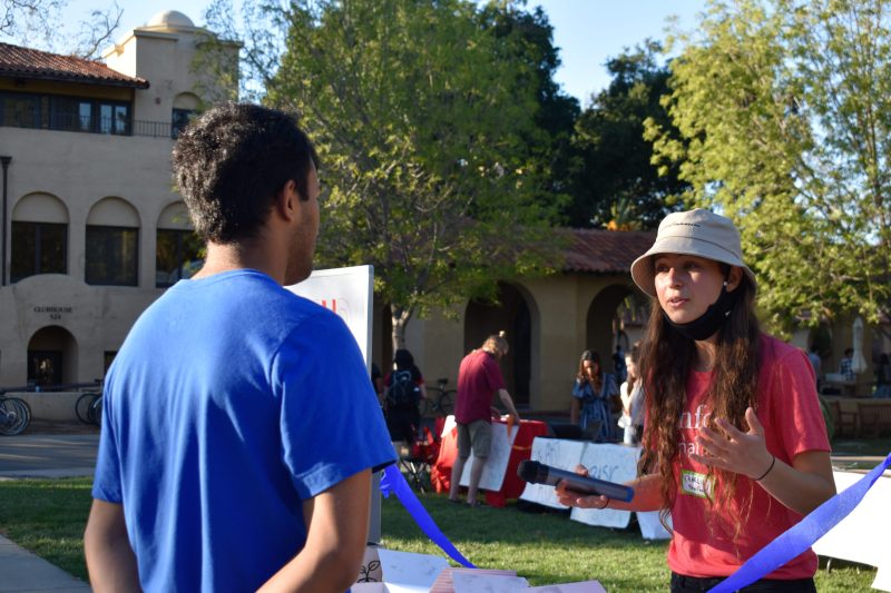 An attendee speaking with a student group member at White Plaza Lawn