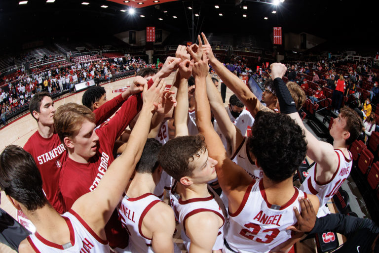 Stanford men's basketball huddles alongside the court.