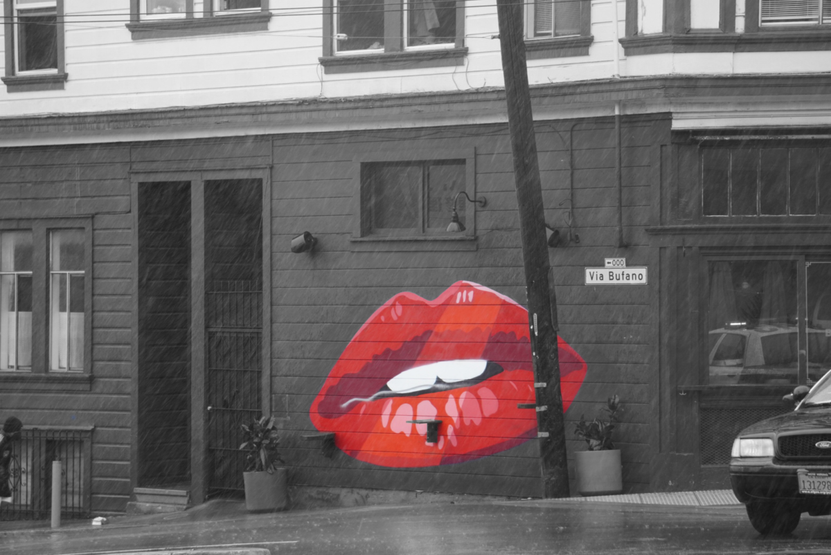Red lip street art on Via Bufano. The lip shines red while everything else is pictured grayscale.