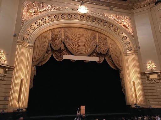 A stage with beige curtains and a dark backdrop.
