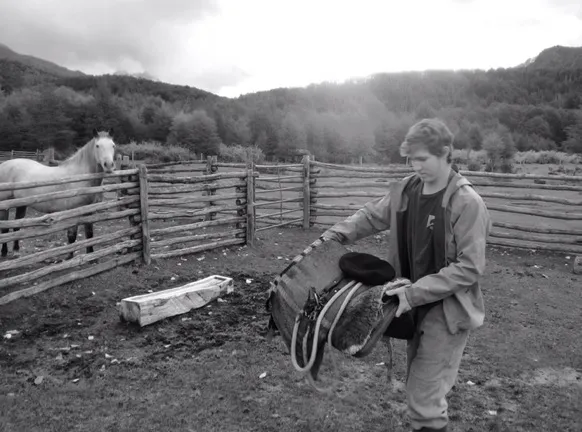 Black and white pic of Caeden working on ranch and a horse in background
