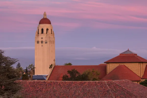 Hoover Tower above sandstone buildings, purple and pink sky in the background