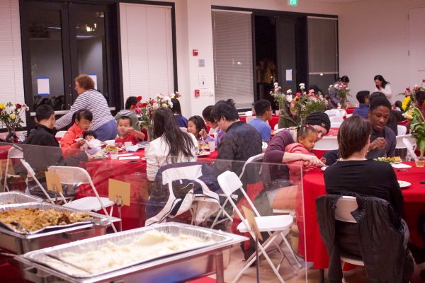 Graduate student families eat Thanksgiving dinner at tables